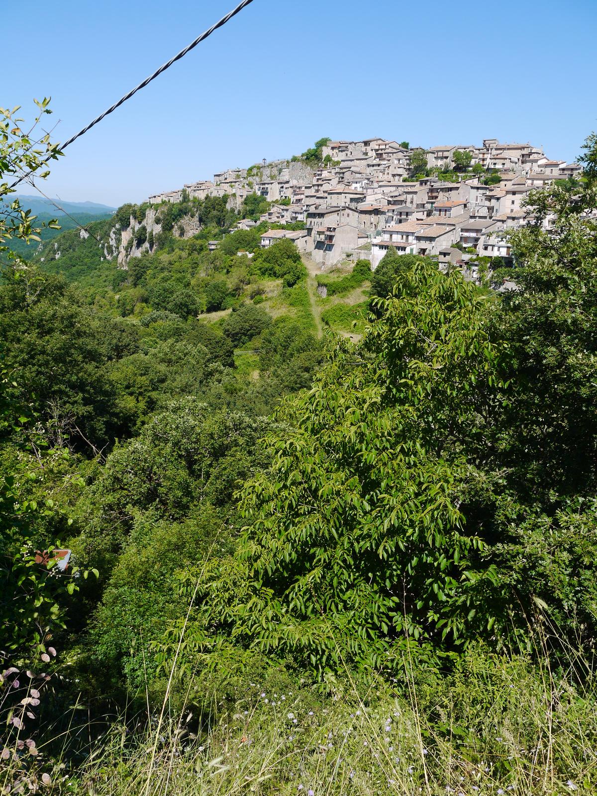 Pietrasecca seen from a distance, perched on its rock spur above the green valley