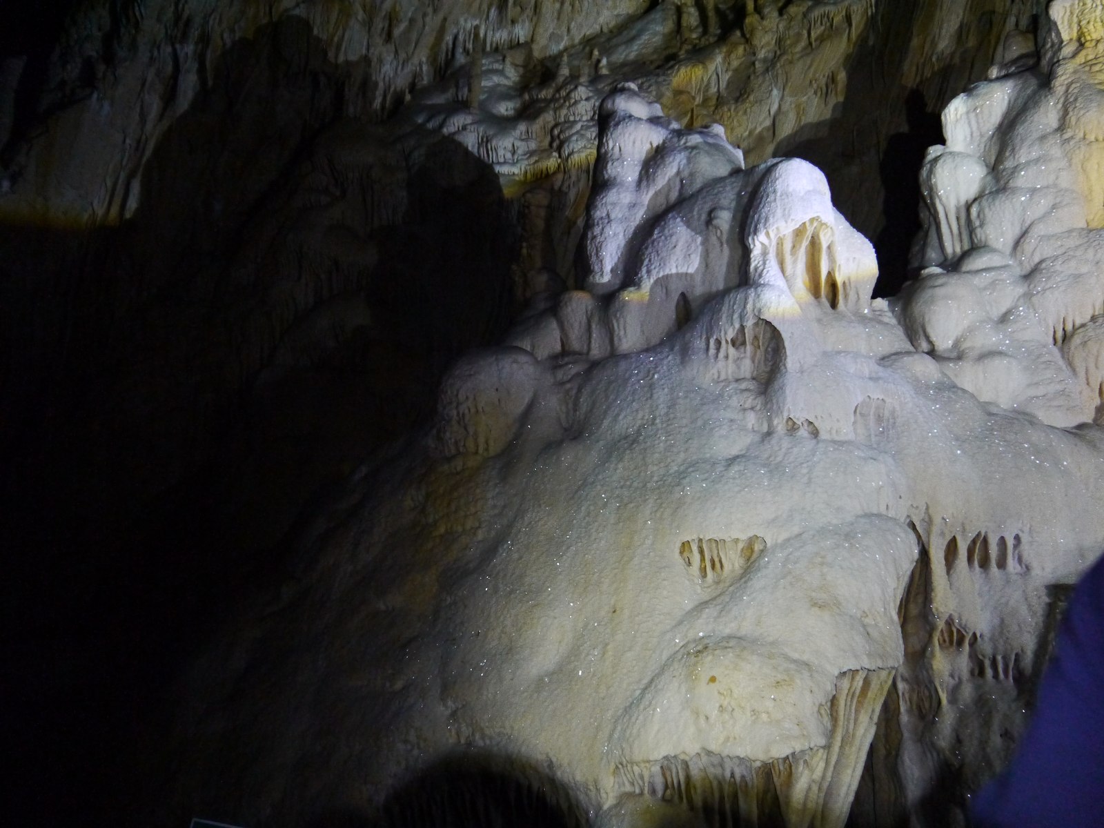 Cave formations rising out of the darkness under a single beam of light