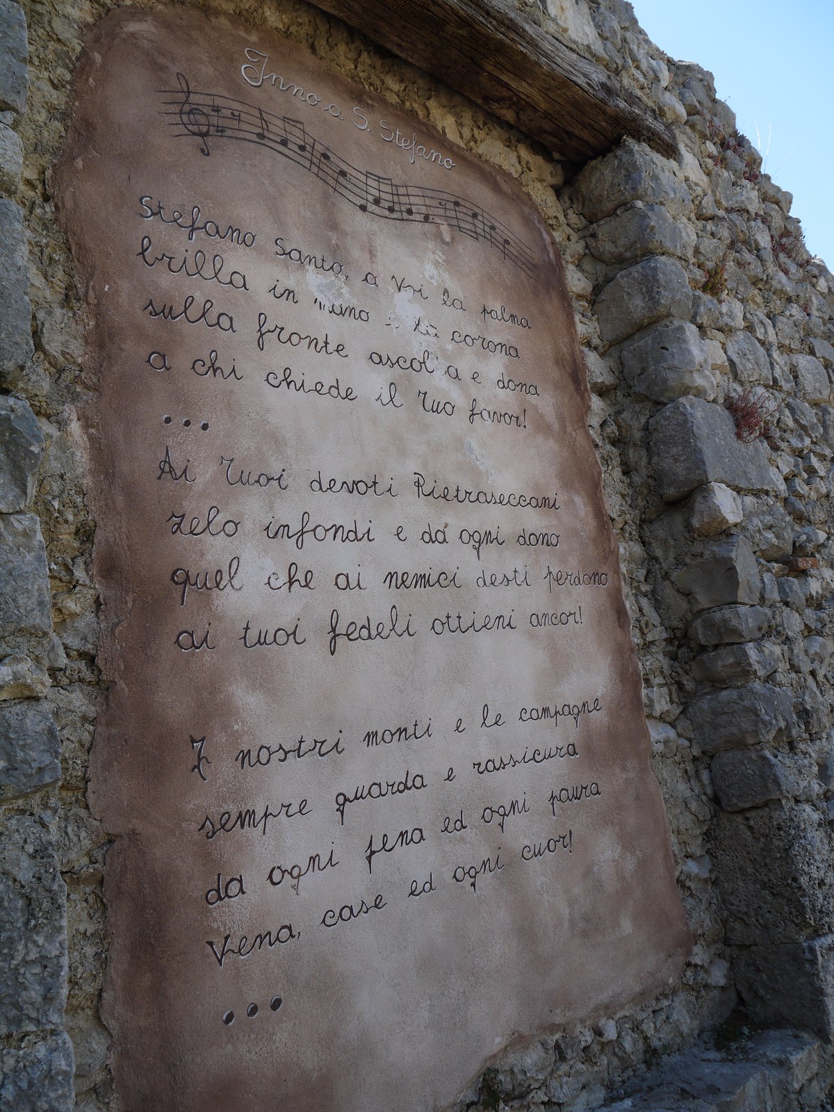 A hand-painted plaque with a hymn dedicated to Santo Stefano set into the ruined wall
