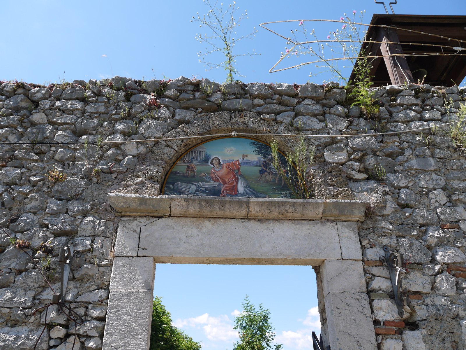 A stone archway in the ruined walls, framing a small painted icon