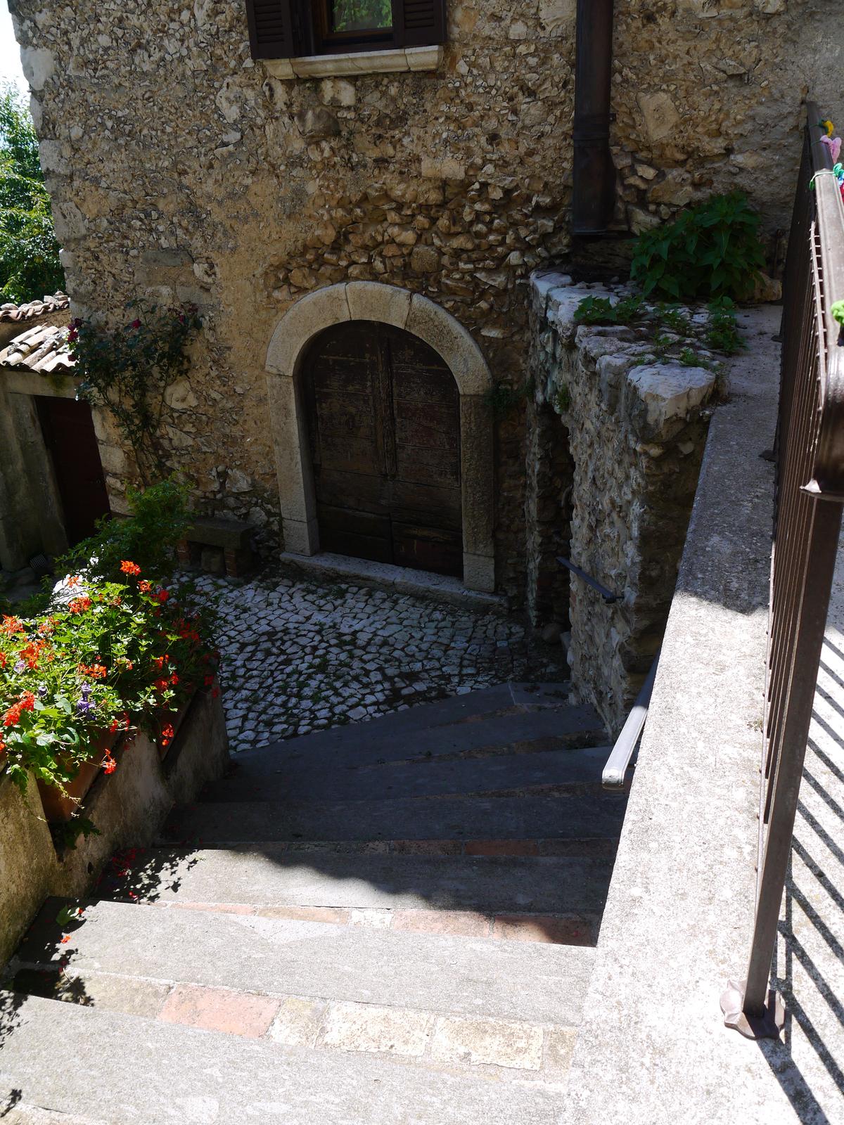 A stone staircase climbing between houses, decorated with pots of flowers